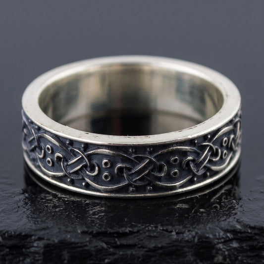 Handmade sterling silver band seen front on, interlace over a blackened ground