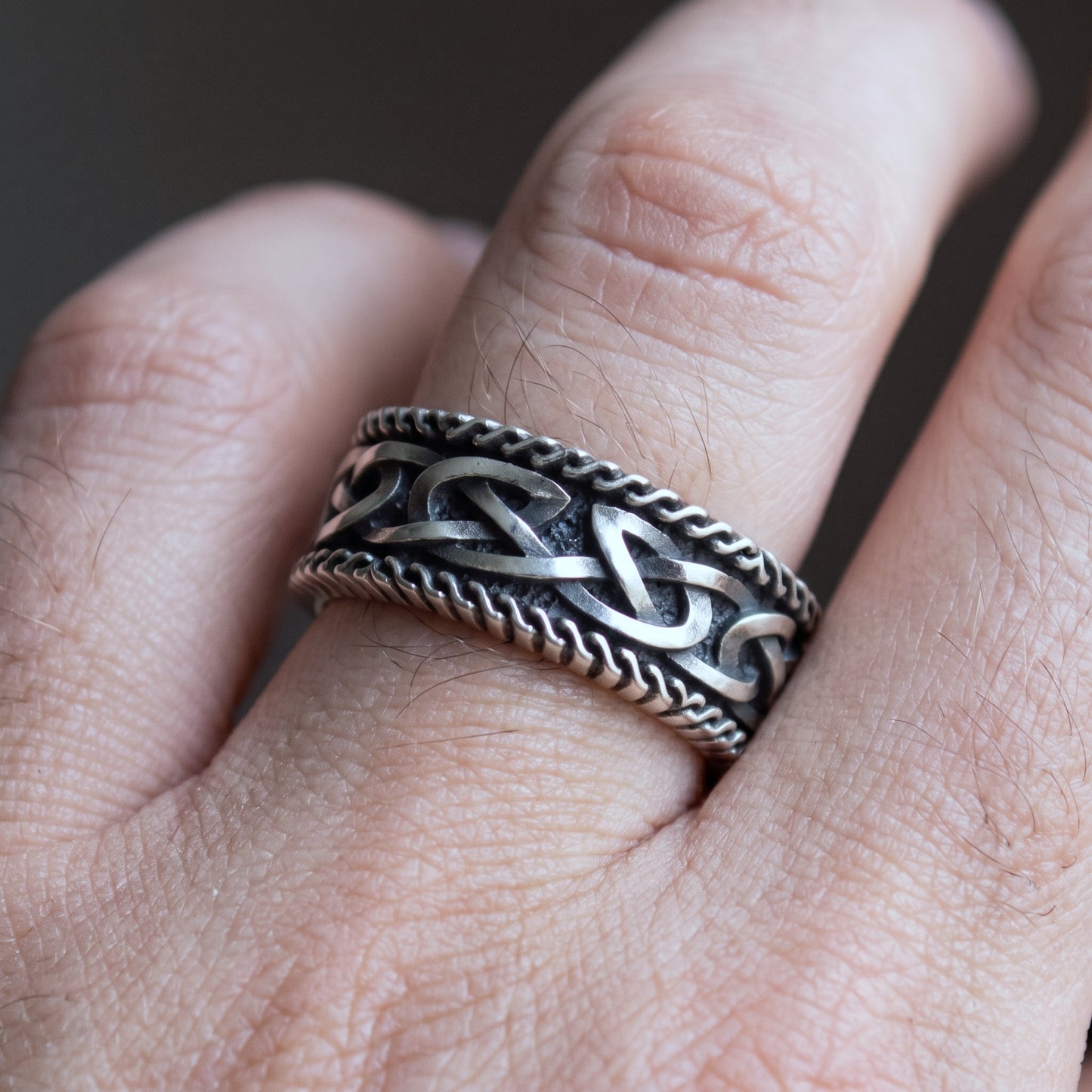 Viking wedding ring worn on a finger, showing the width of the oxidised sterling silver band
