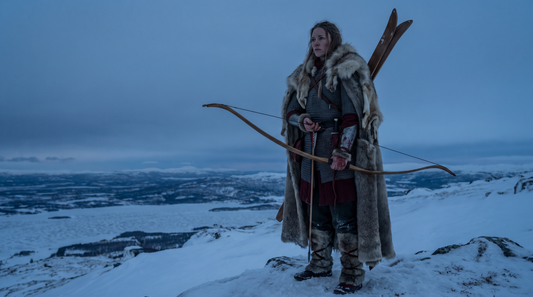 Skadi the Norse winter goddess with bow and skis on a snowy mountain ridge at dusk