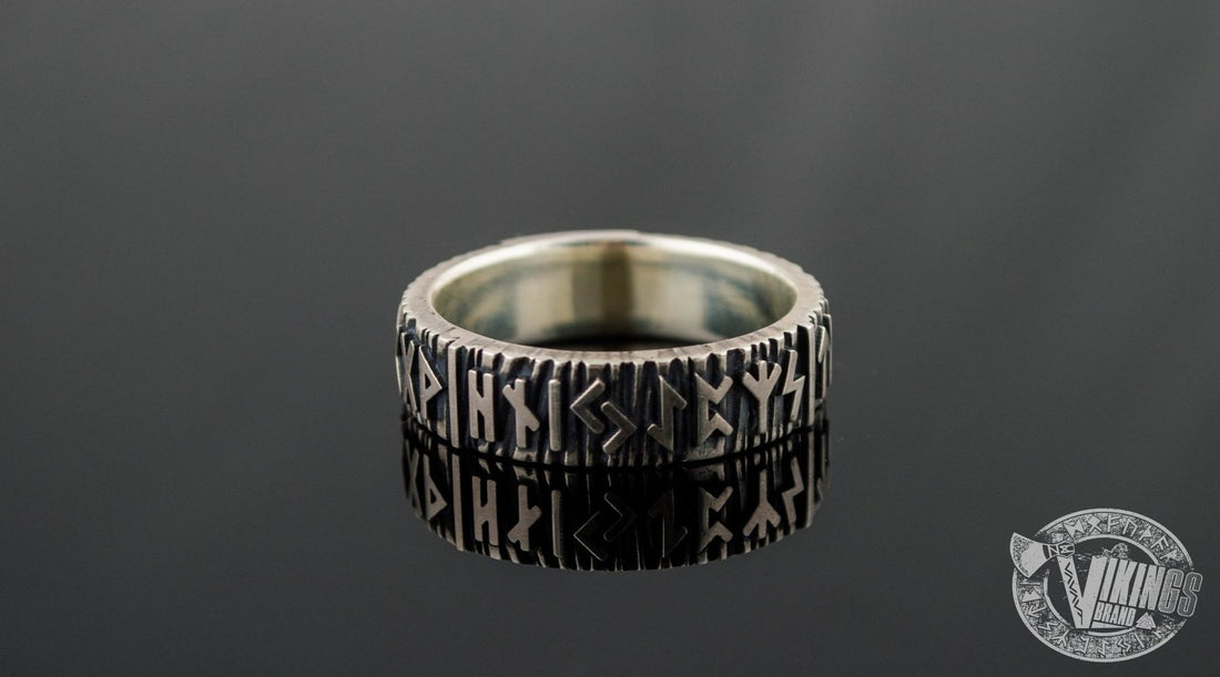Elder futhark runes carved in a silver Viking ring on black background.