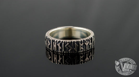 Elder futhark runes carved in a silver Viking ring on black background.