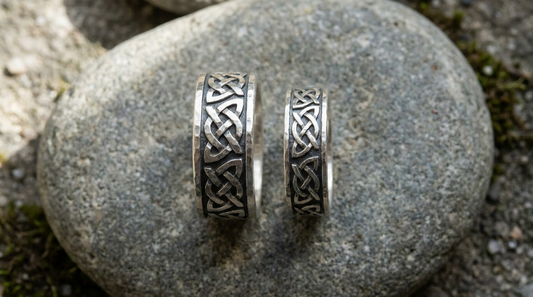 Two silver bands with the same knotwork on grey stone, one wide and one narrow
