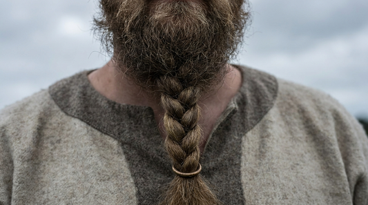 A braided Viking beard closed with a single plain bronze ring, against an undyed wool tunic
