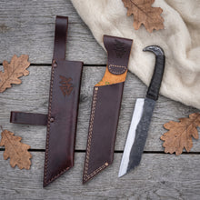 Broken-Back Viking seax knife laid out with both leather sheaths — the belt sheath with riveted loop and the plain slip sheath — on weathered grey planks