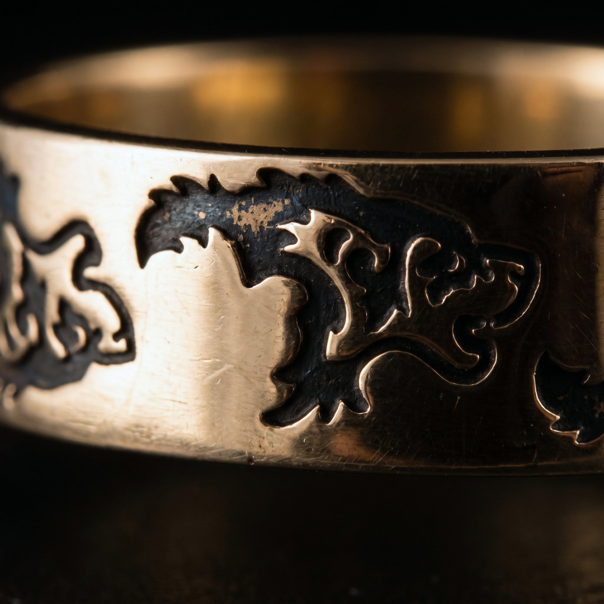 Macro of two stylised Norse wolves engraved and darkened into the bronze band