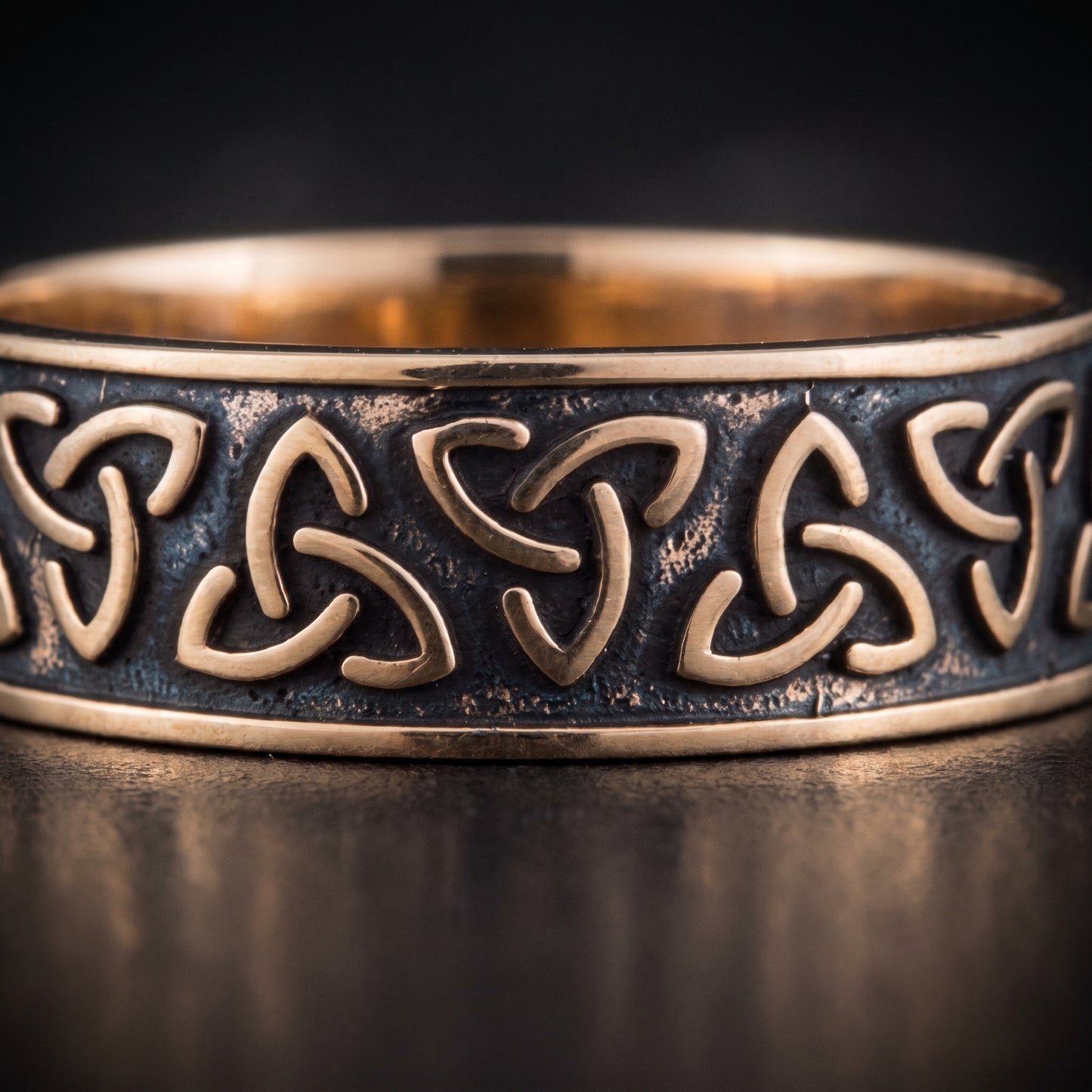 Macro of the raised bronze triquetra knots on the dark oxidised channel