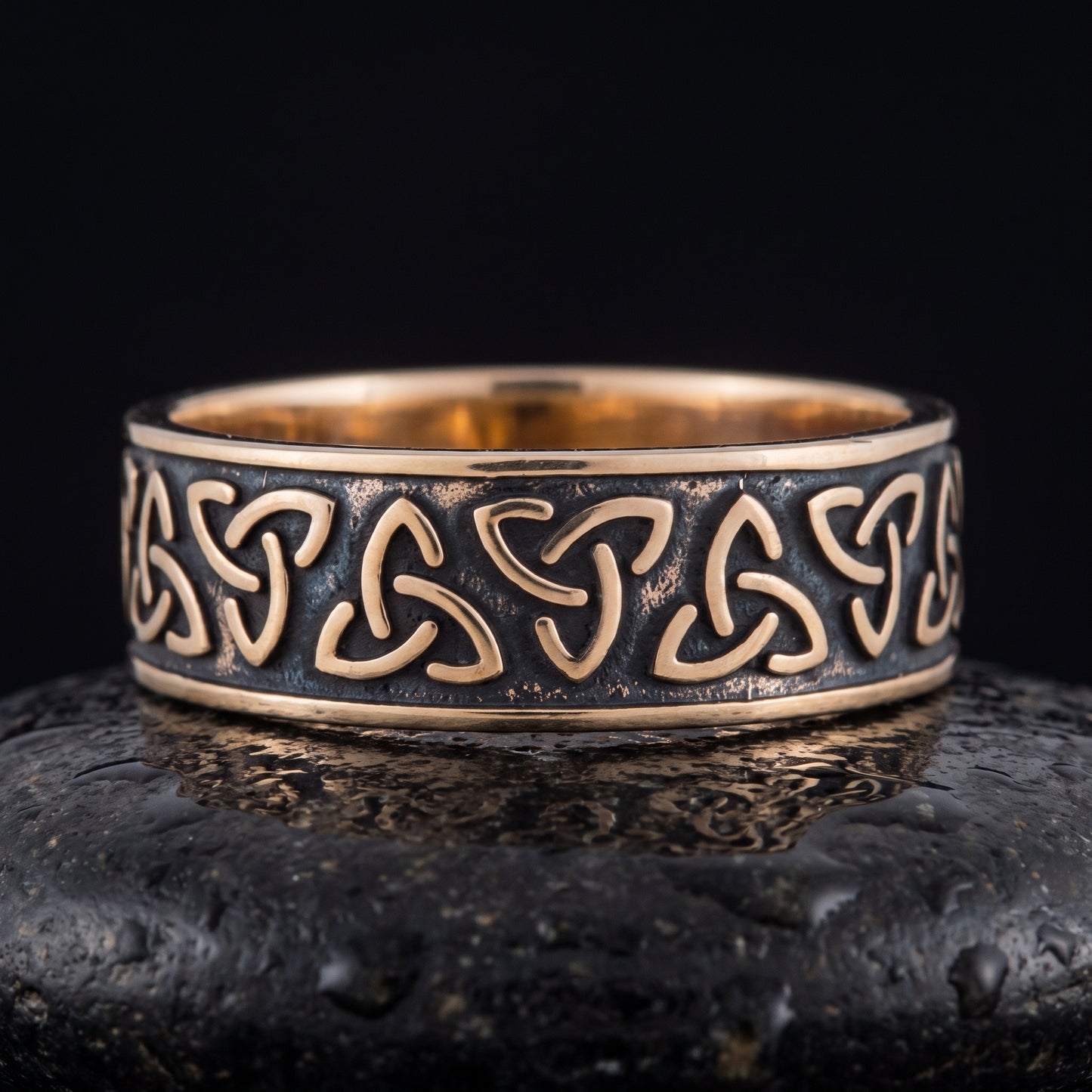 Handmade bronze triquetra ring seen front on, oxidised channel between polished rails