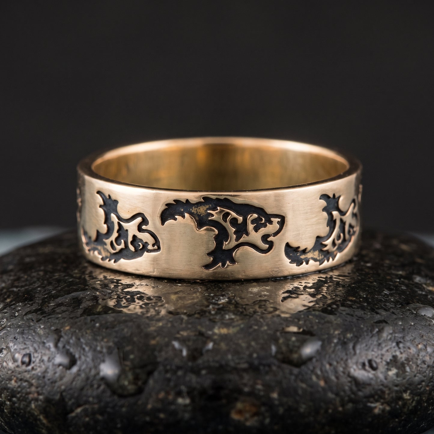 Handmade bronze Viking ring seen front on, a row of stylised wolves engraved into the flat band