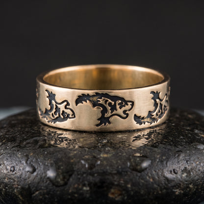 Handmade bronze Viking ring seen front on, a row of stylised wolves engraved into the flat band