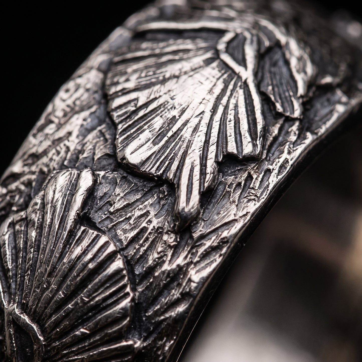 Macro of the carved wolf head and swept mane on the silver Fenrir band