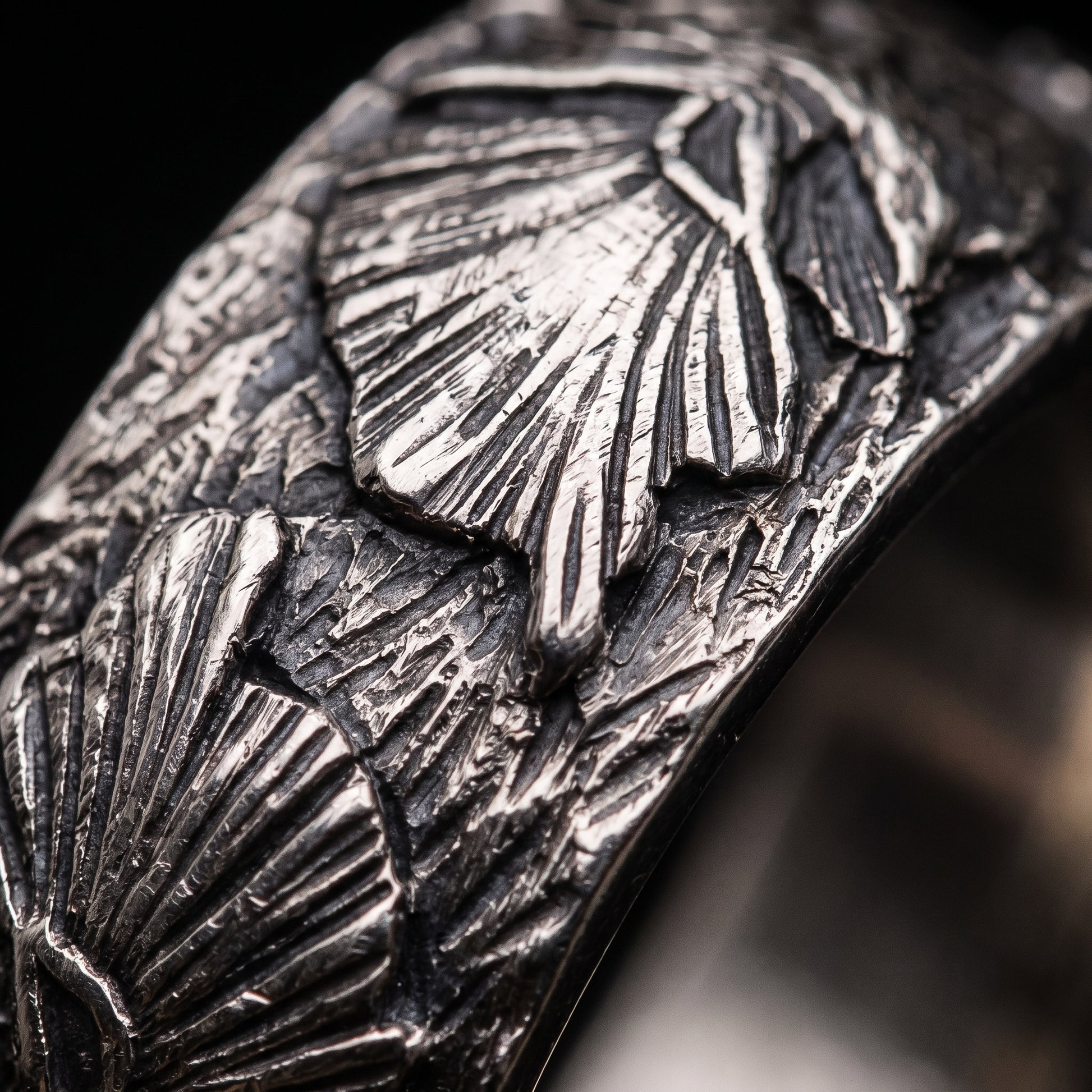 Macro of the carved wolf head and swept mane on the silver Fenrir band