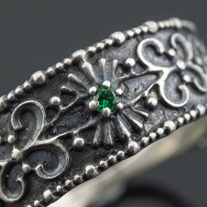 Macro of the green gem in its radiating panel and the beaded silver filigree