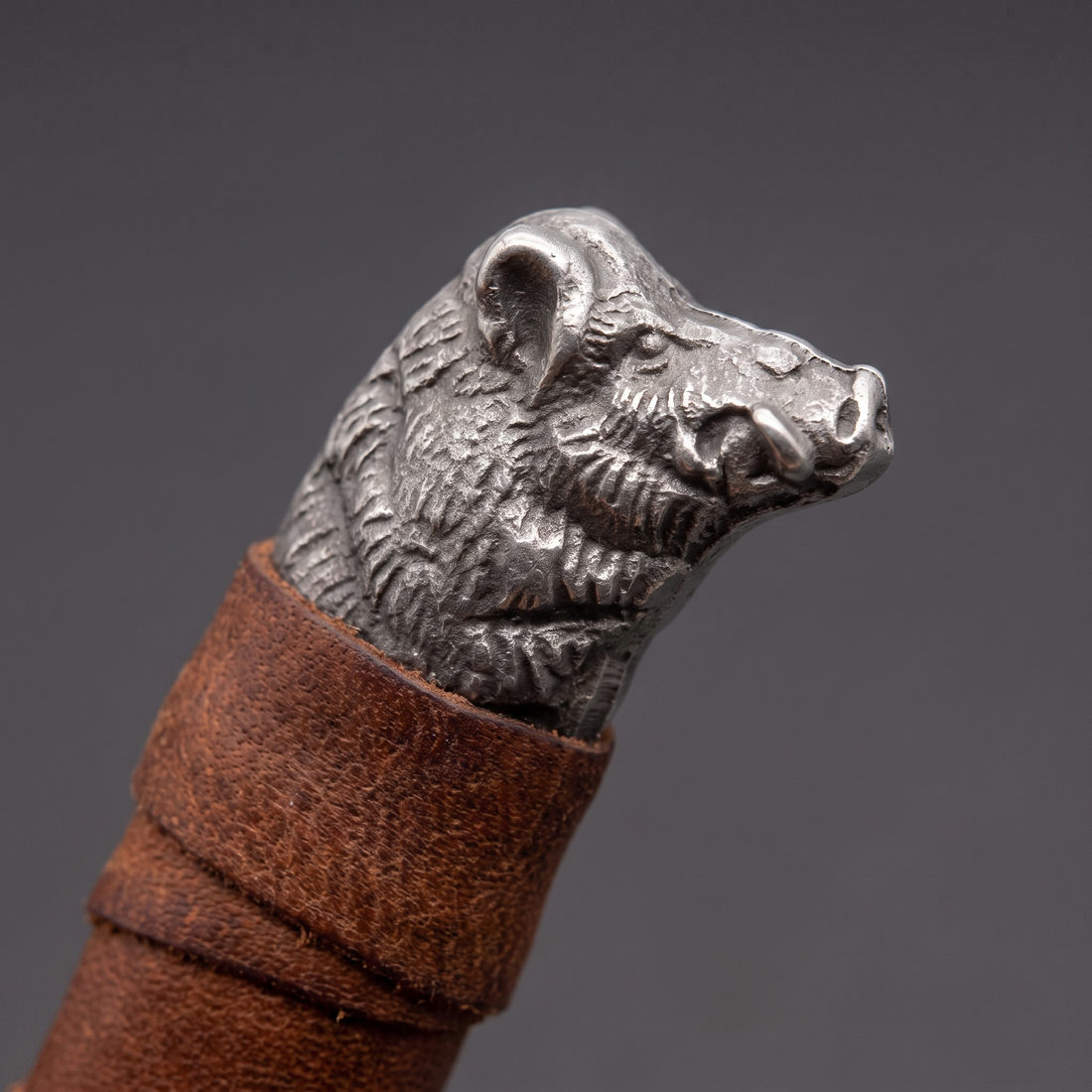 Cast boar's head pommel and leather-wrapped grip of the Boar's Head seax
