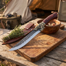 Fenrir boning knife and its leather sheath on a chopping board at a camp table with fresh thyme