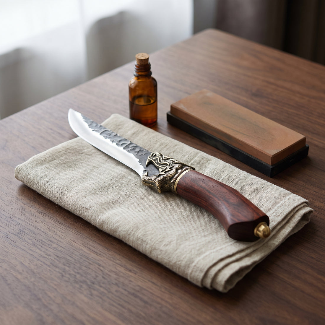 Caring for the Fenrir boning knife: the knife on linen beside an oil bottle and a sharpening whetstone