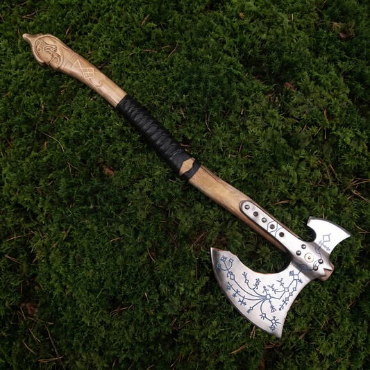 Full-length view of the hand-forged Kratos axe, a Viking-style engraved axe, lying on green moss