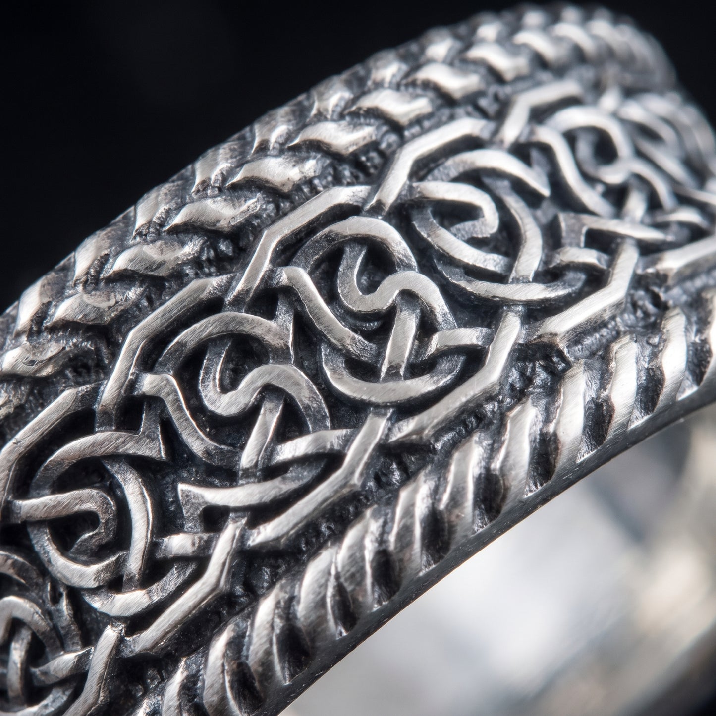 Macro of the interlaced Norse knotwork and twisted rope rails on the silver band