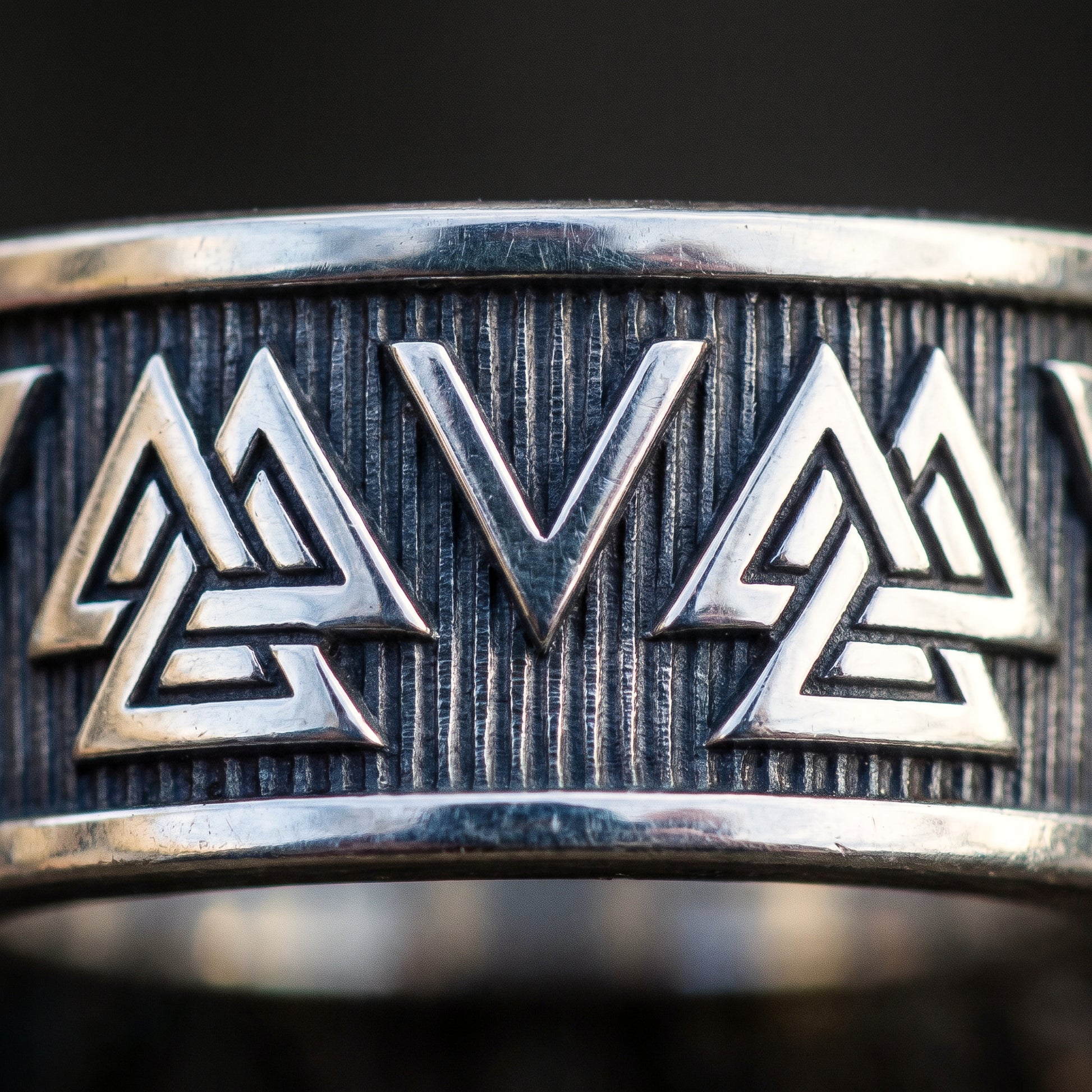 Macro of two Valknut symbols of three interlocking triangles on the silver band