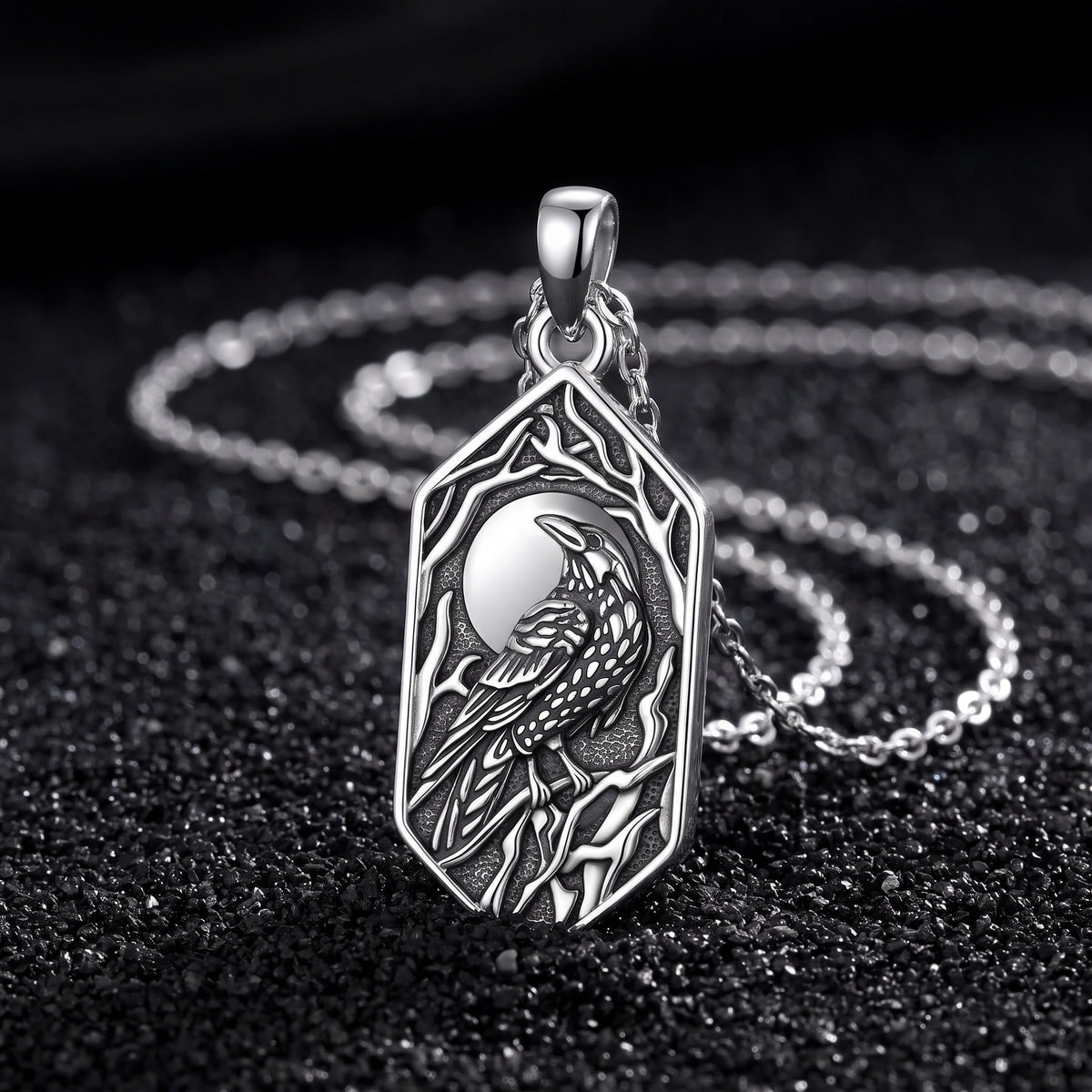 Raven and moon pendant in 925 sterling silver standing on black volcanic sand with its thin silver chain