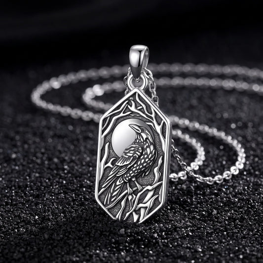 Raven and moon pendant in 925 sterling silver standing on black volcanic sand with its thin silver chain
