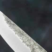 Macro view of the dark forge skin meeting the hand-ground bevel on the Raven's Beak seax carbon steel blade
