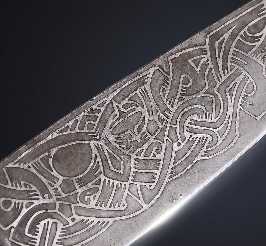 Close-up of the acid-etched interlaced ravens and Norse knotwork on the Raven-Hilt seax carbon steel blade