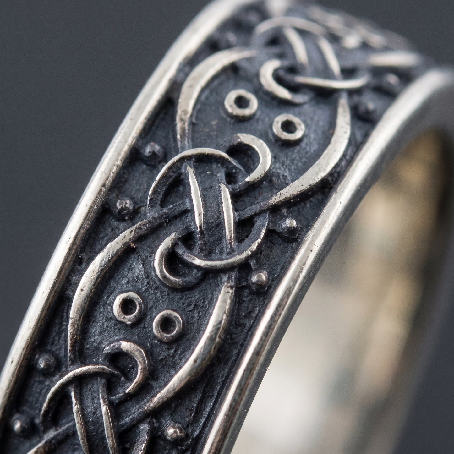 Macro of the woven silver ribbon interlace and punched pellets on the dark ground