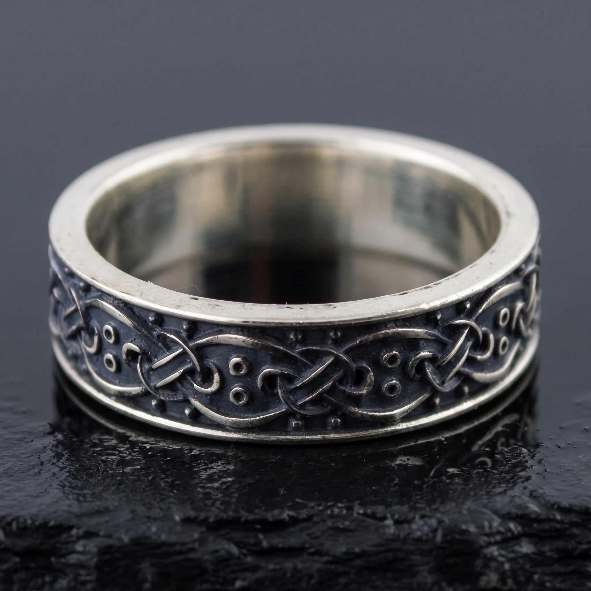 Handmade sterling silver band seen front on, interlace over a blackened ground