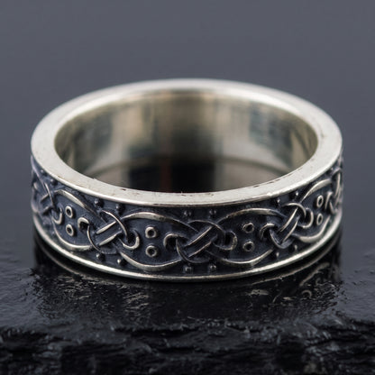 Handmade sterling silver band seen front on, interlace over a blackened ground