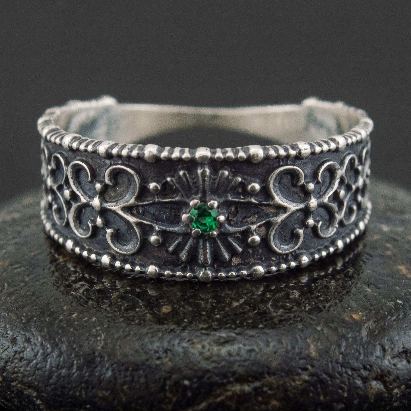 Handmade 925 silver ring seen front on, filigree ornament and a set green gem