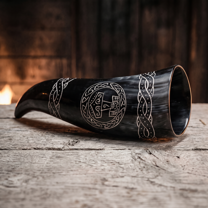 Black Viking drinking horn engraved with Thor's hammer, lying on an oak board