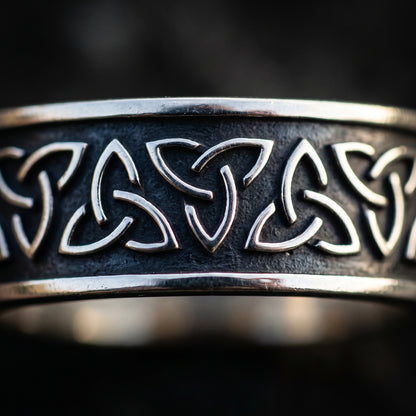 Macro of the linked triquetra knots on the narrow silver band