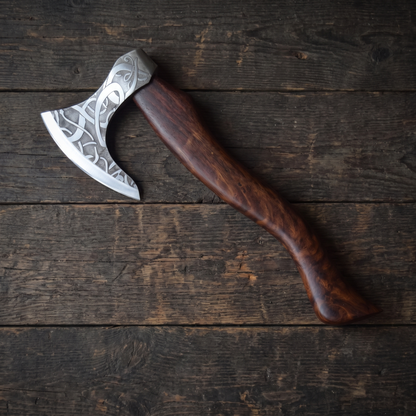 Full-length view of the 18 in Valhalla bearded axe, an etched Viking-style axe, lying on dark timber