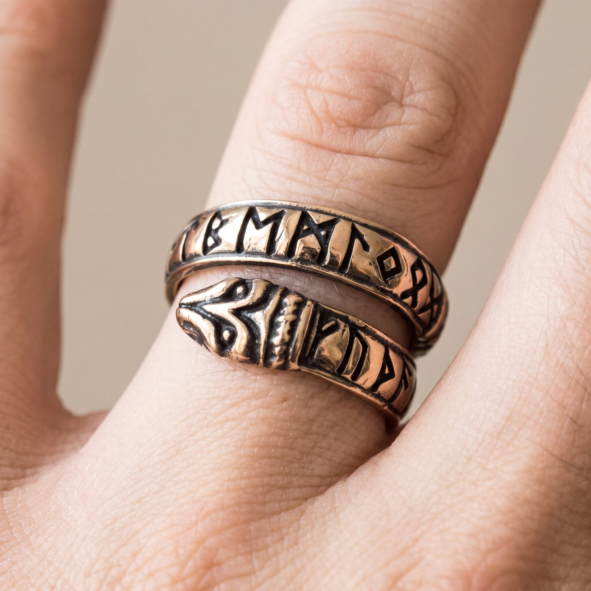 Bronze Ouroboros ring with runes worn on a finger