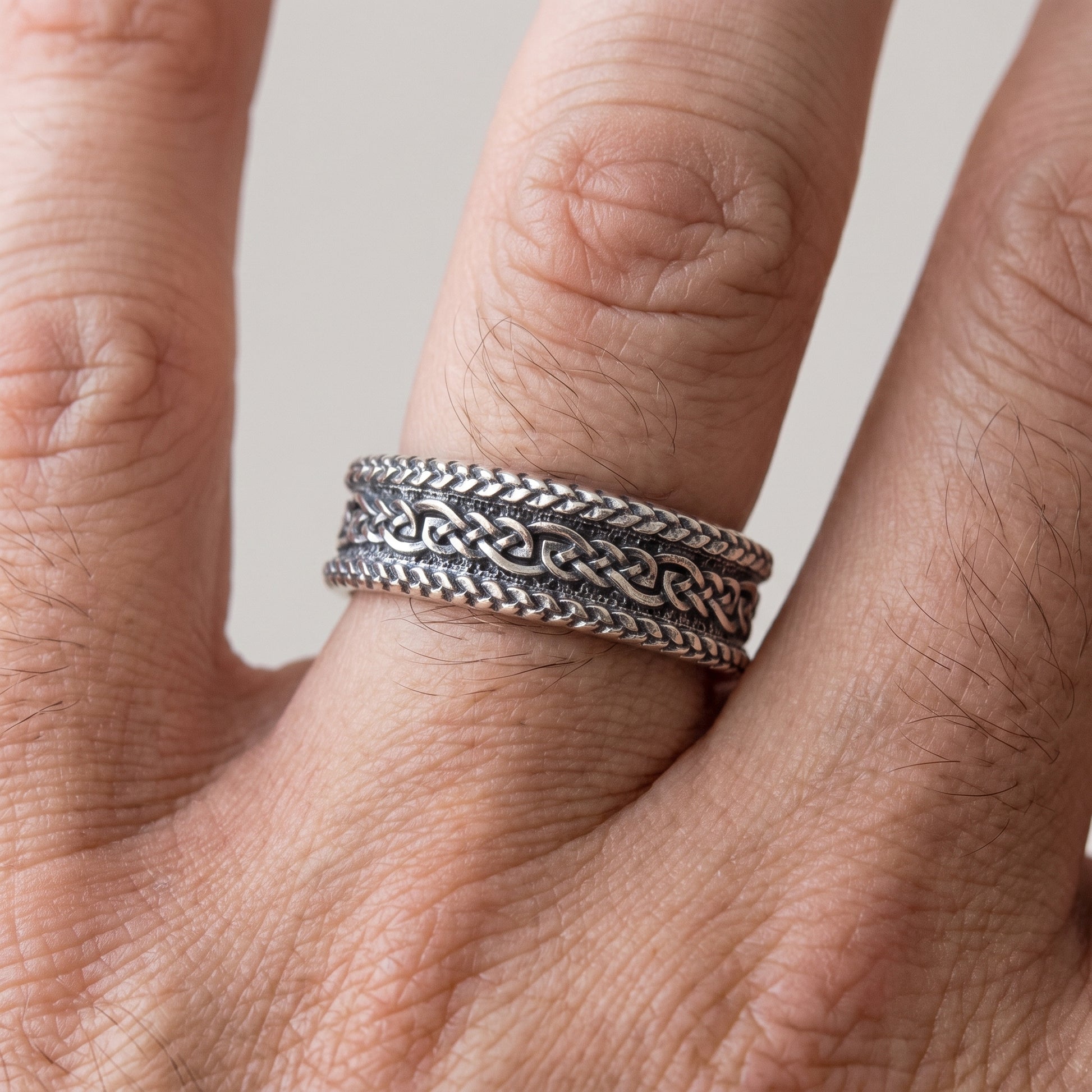Braided silver Viking wedding ring worn on a finger