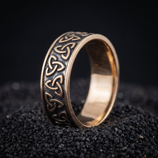 Bronze Viking wedding ring with a chain of triquetra knots on black volcanic sand