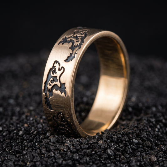 Bronze Viking wedding ring with engraved Norse wolf ornament on black volcanic sand