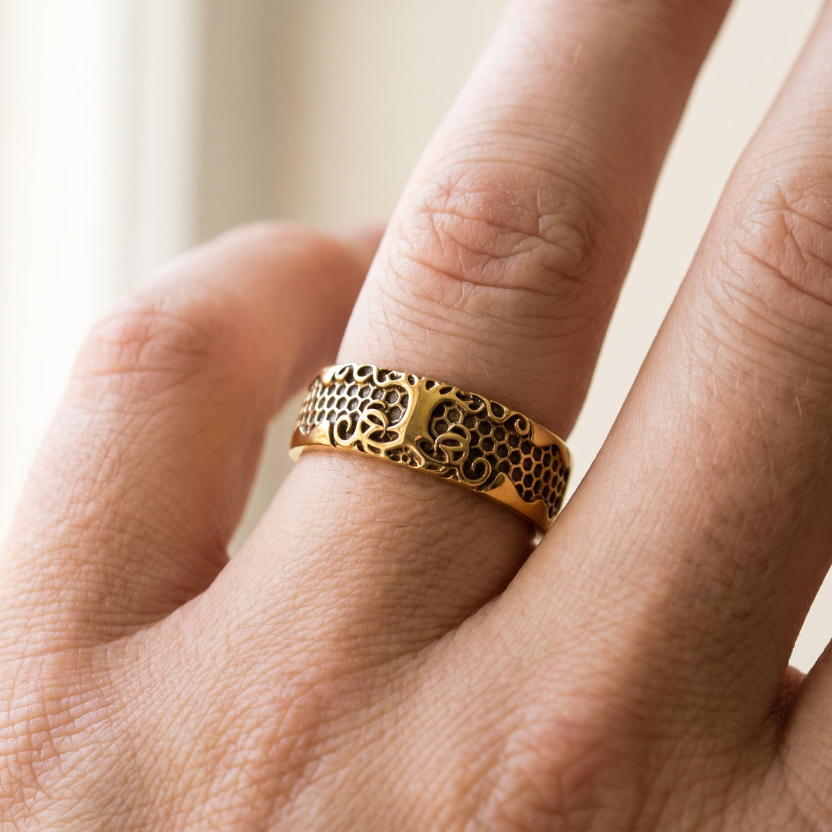 Gold Viking ring with scale and scroll ornament worn on a finger