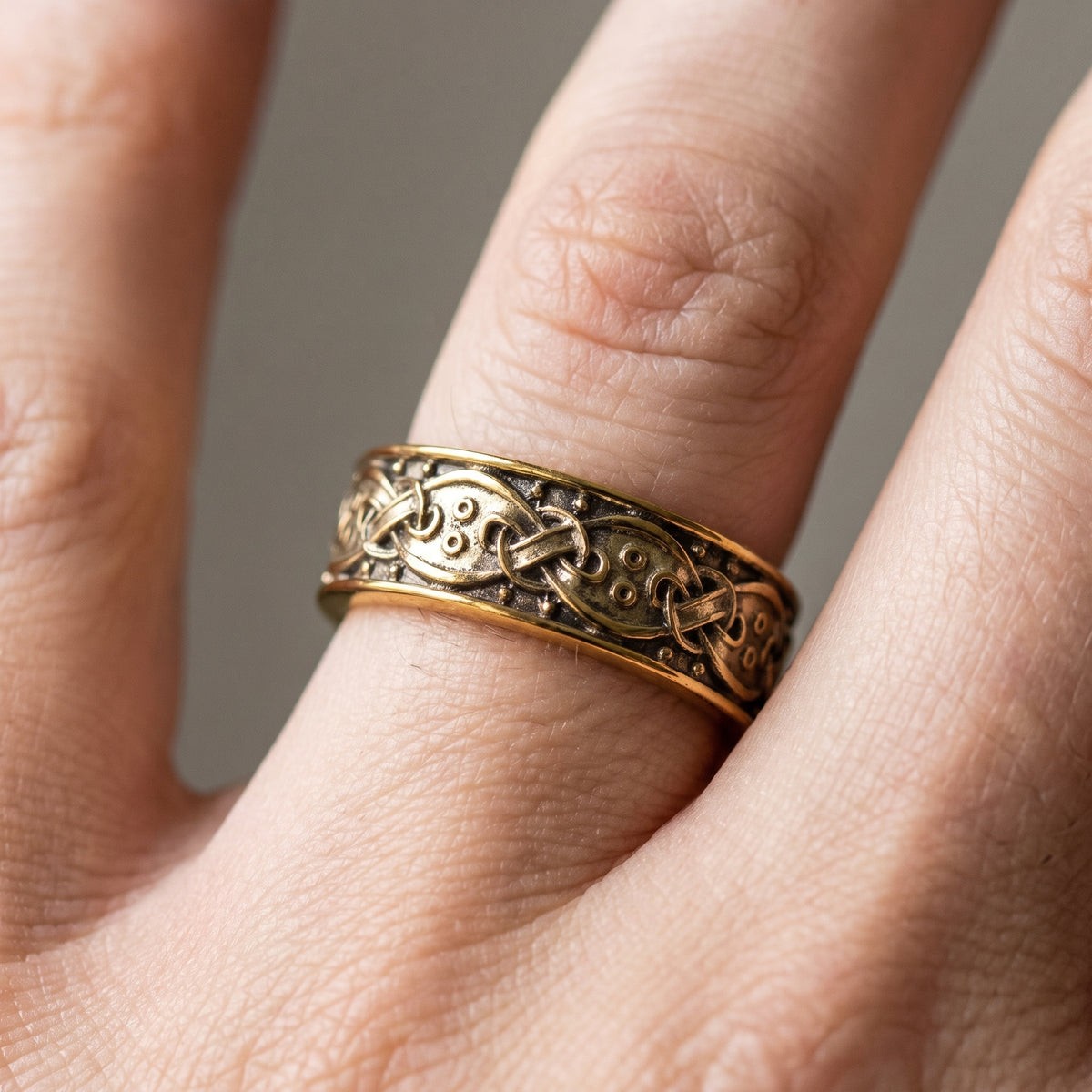 Gold Viking wedding ring with Norse knotwork worn on a finger