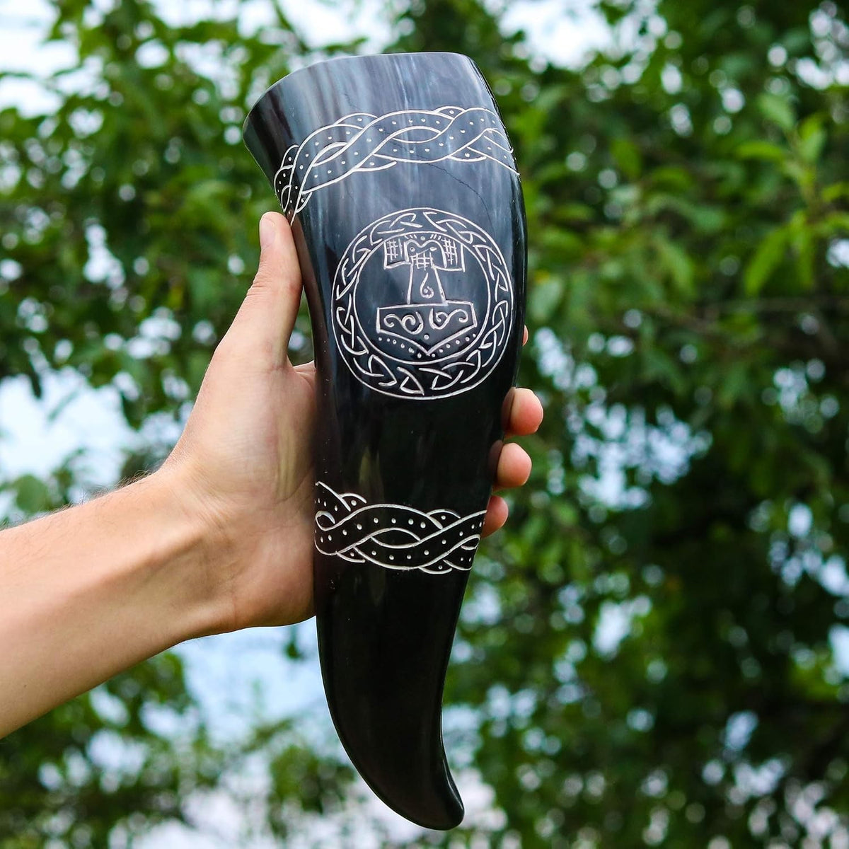 Hand holding the 12 inch Thor's hammer drinking horn outdoors