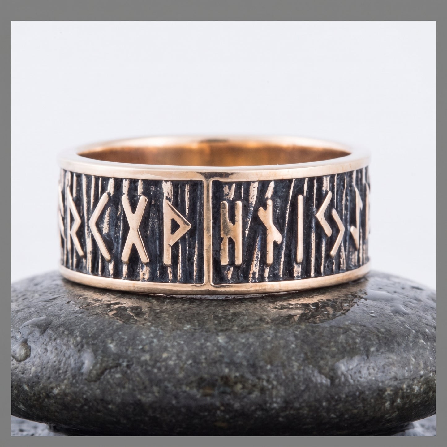 Bronze rune ring seen front on, a row of raised Elder Futhark runes on a dark striated ground