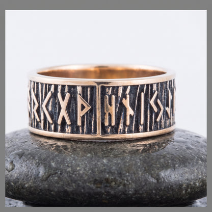 Bronze rune ring seen front on, a row of raised Elder Futhark runes on a dark striated ground