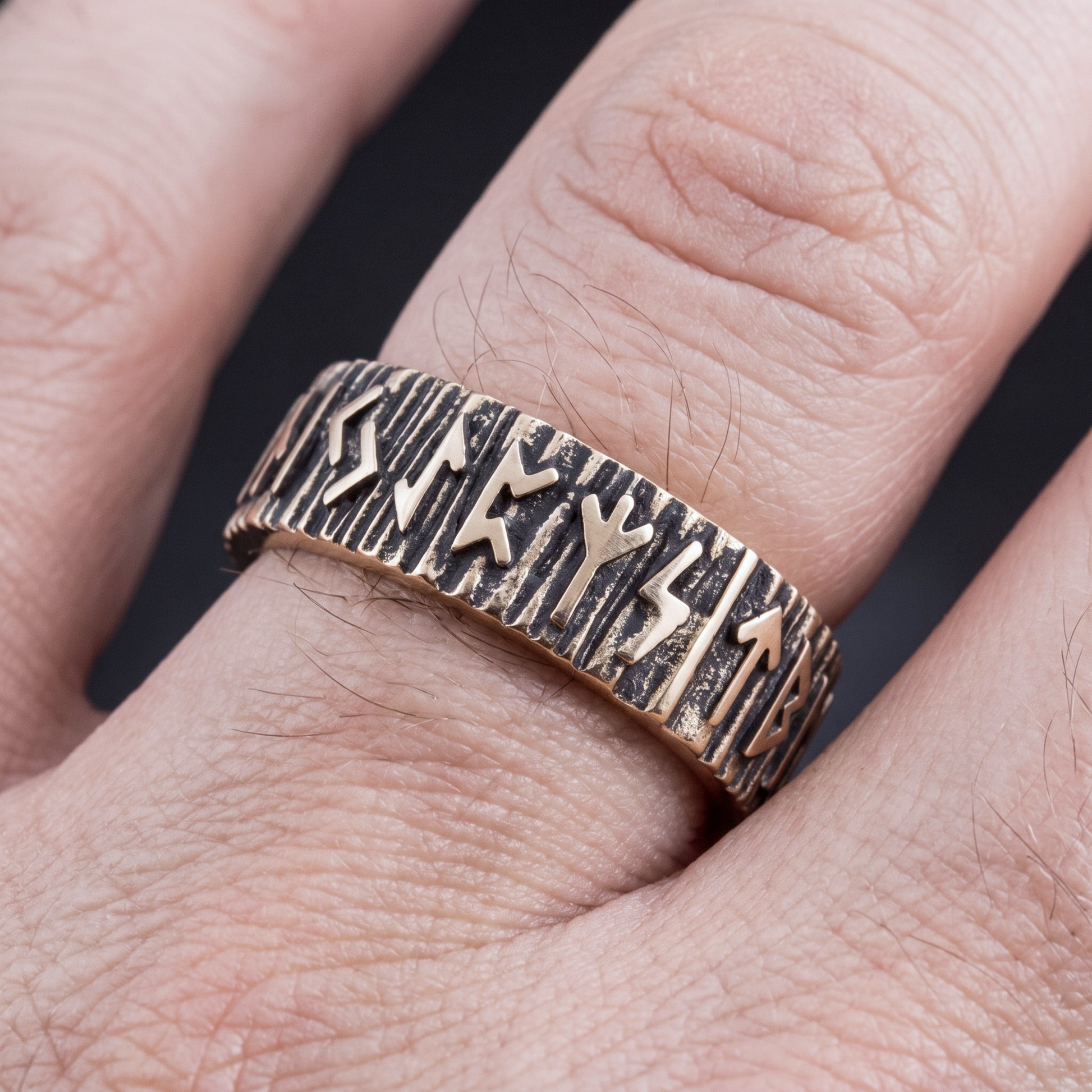 Bronze Elder Futhark rune wedding ring worn on a finger, showing the width of the band