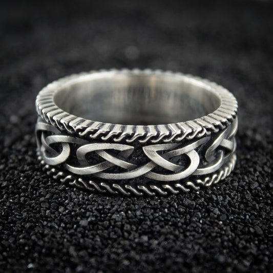 Norse knotwork Viking wedding ring in 925 sterling silver, twisted rope borders, on black volcanic sand