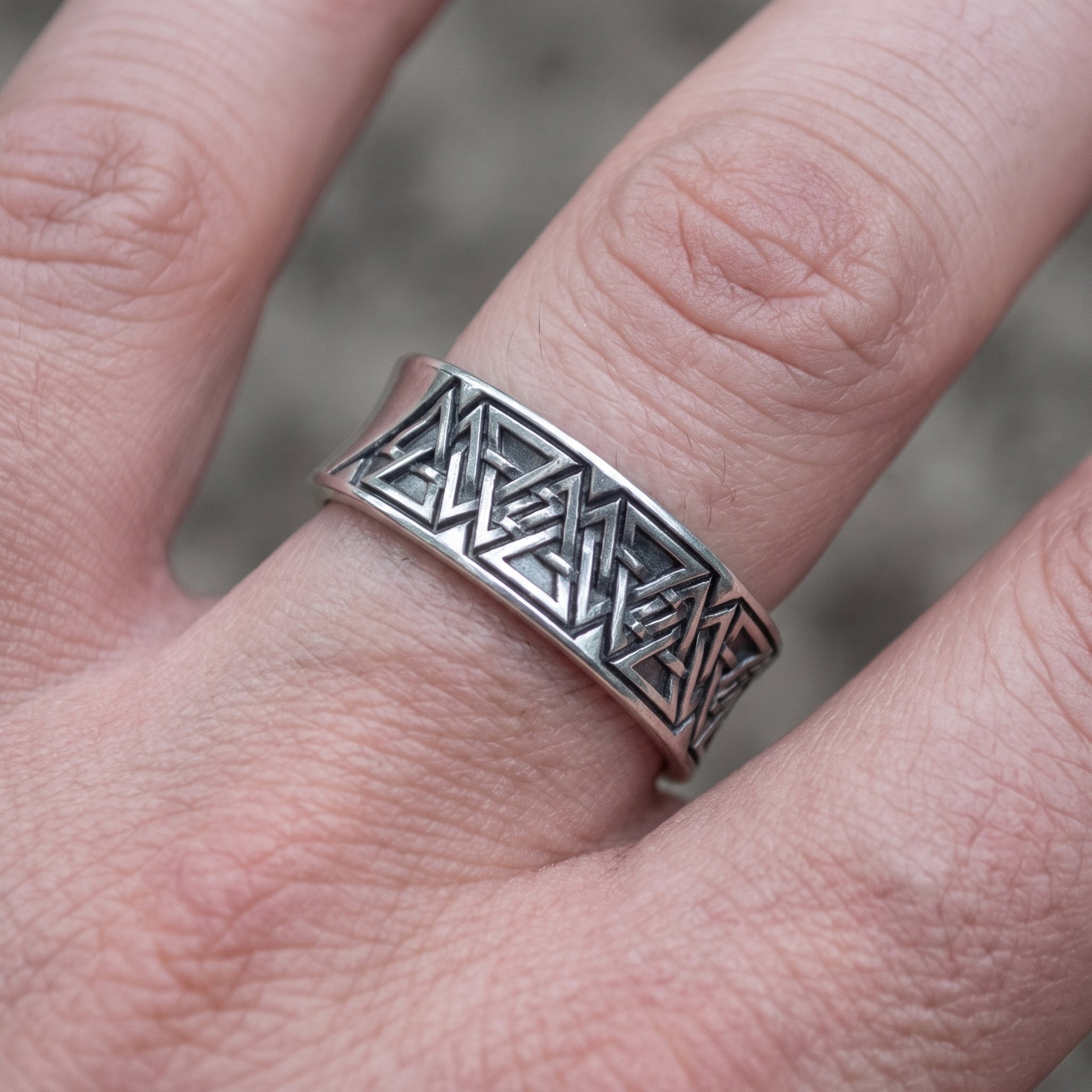 Valknut rune band ring worn on a finger, showing the width of the silver band