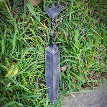 Viking dagger lying in grass, showing the twisted steel grip and flat forged pommel