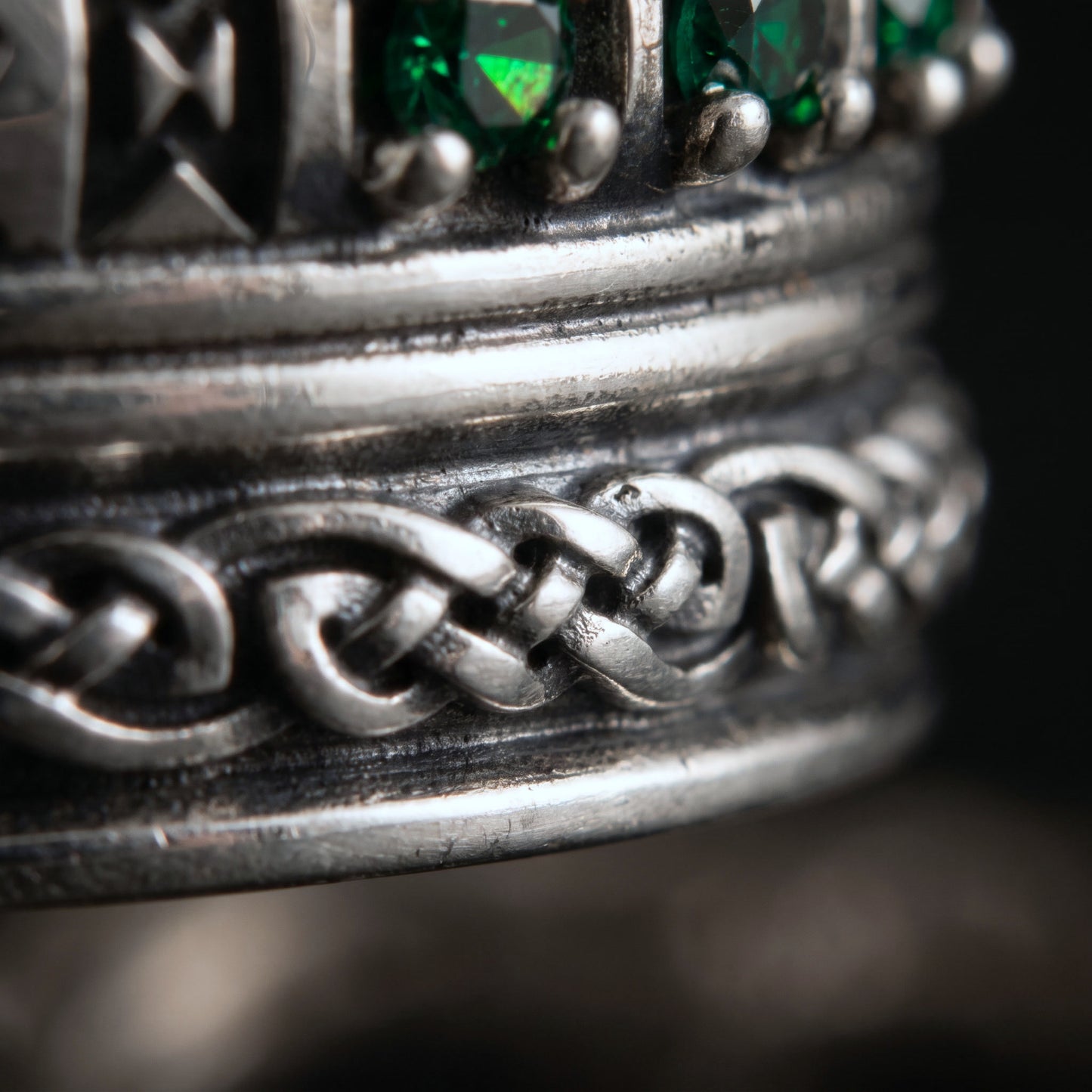 Macro of the plaited knotwork rope and green cubic zirconia on the silver Viking ring