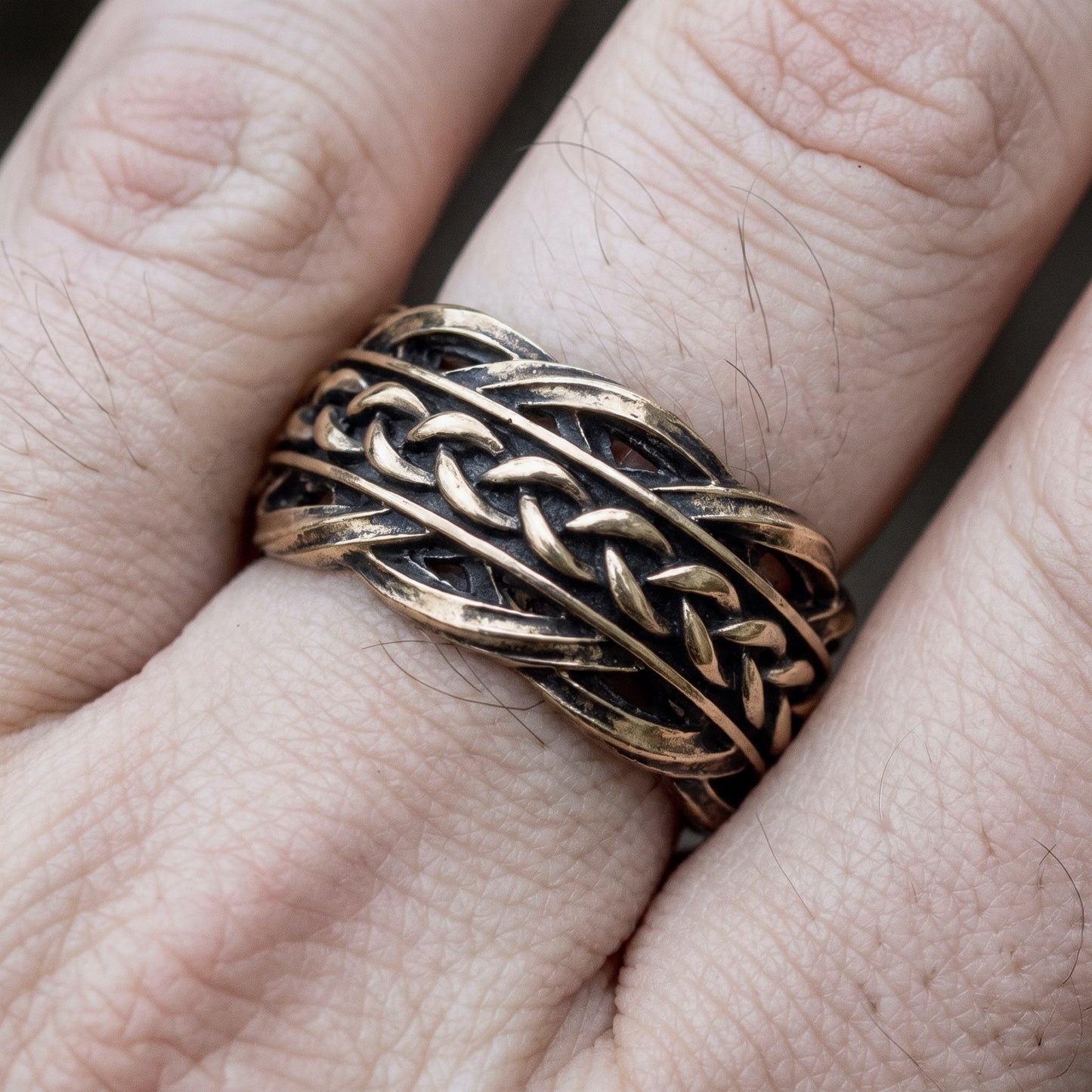 Bronze Viking wedding ring worn on a finger, showing the width of the woven band