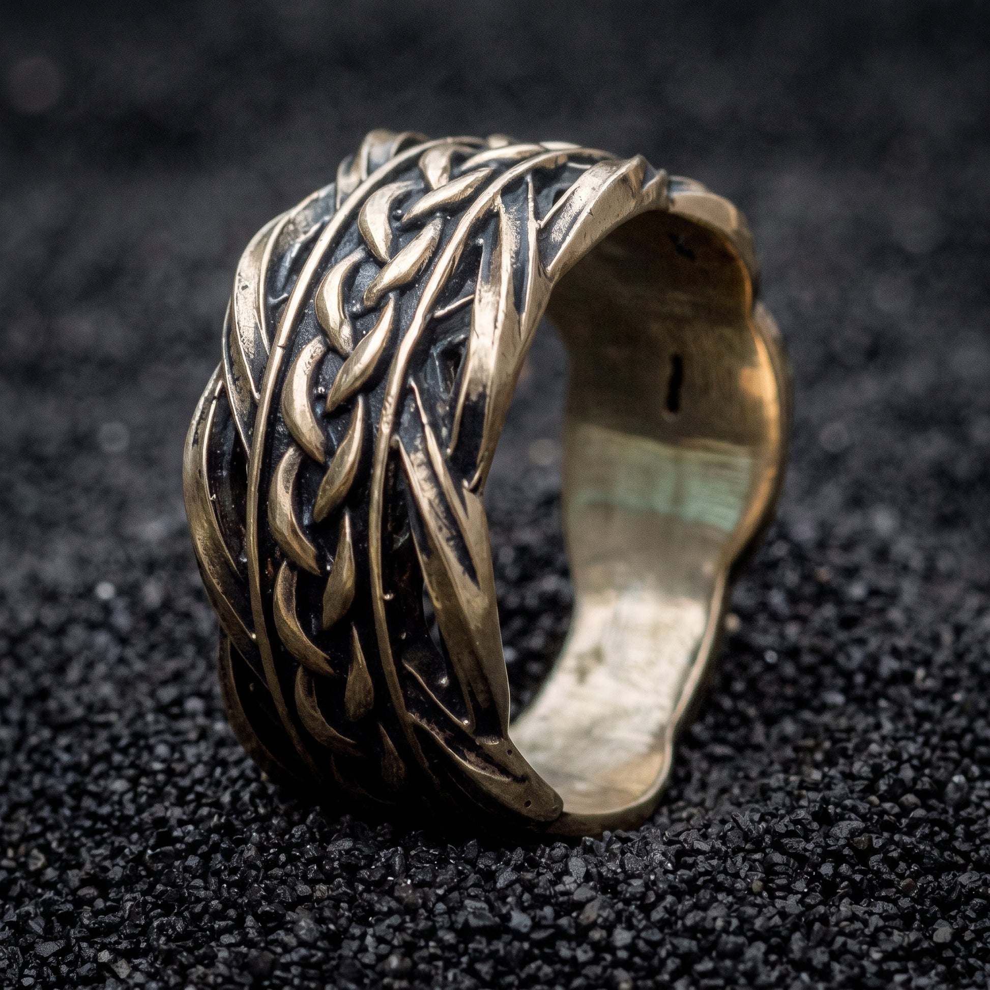 Bronze Viking wedding ring with woven Scandinavian ornament on black volcanic sand
