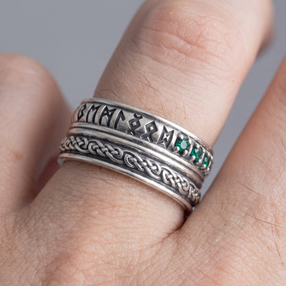 Silver Viking wedding ring with runes and green cubic zirconia worn on a finger